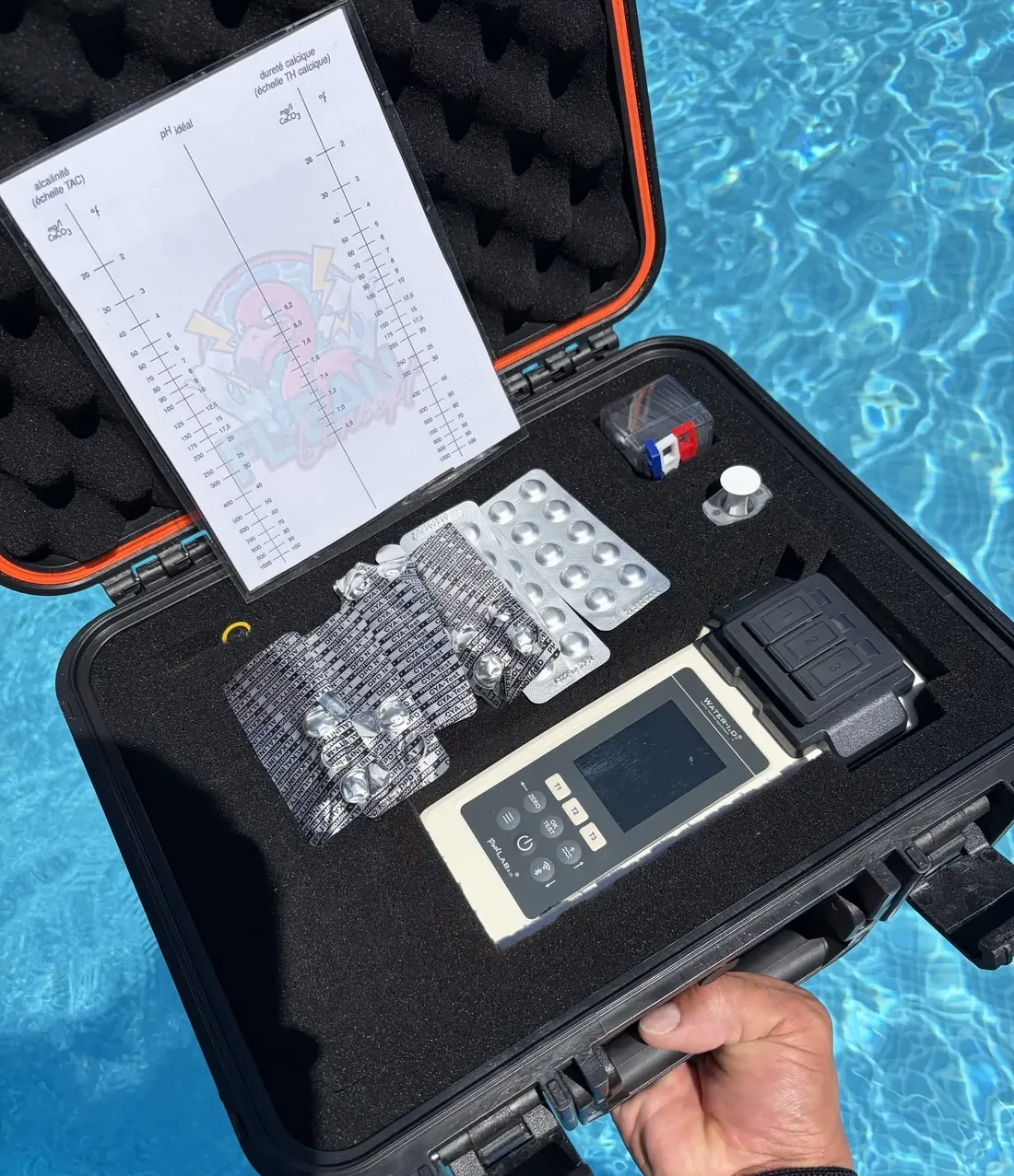 Mallette d'analyse de l'eau ouverte au bord d'une piscine, avec photomètre et pastilles de test